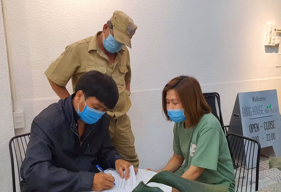 Lực lượng chức năng xã, phường ký cam kết với cơ sở kinh doanh chấp hành quy định phòng chống dịch Covid 19. Ảnh: Bá Bính