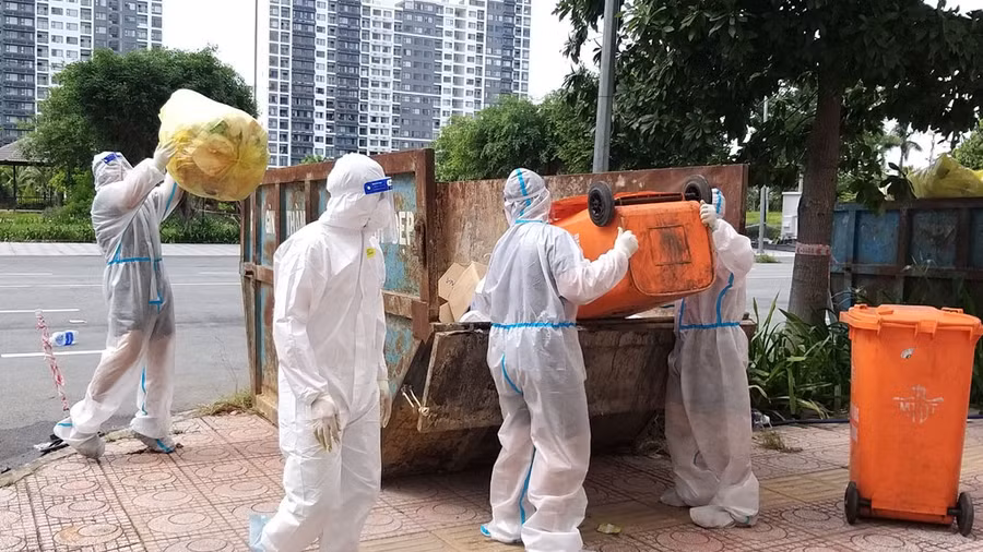 Thành viên đội hậu sự tham gia cùng dân quân tự vệ đổ rác cho bệnh nhân. Ảnh: Như Lịch