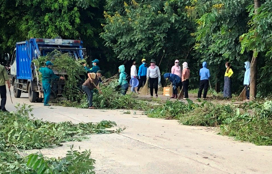 Lực lượng dân quân và đoàn viên thanh niên cắt tỉa cây xanh. Ảnh: HL