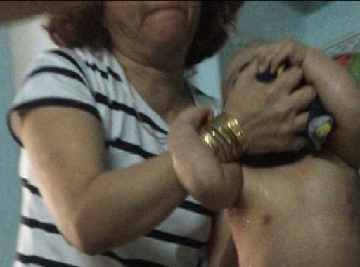 Hình ảnh một bảo mẫu tại điểm giữ trẻ Mẹ Mười xách đầu cháu bé. Ảnh: K.H.N.T. 