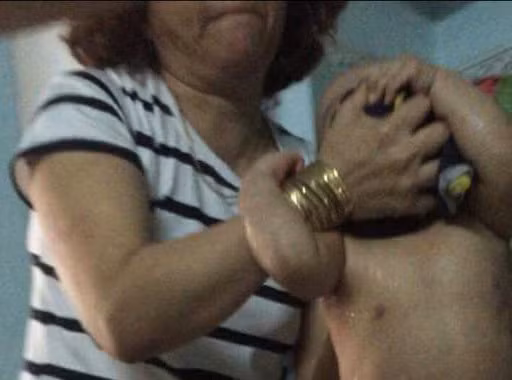 Hình ảnh một bảo mẫu tại điểm giữ trẻ Mẹ Mười xách đầu cháu bé. Ảnh: K.H.N.T. 