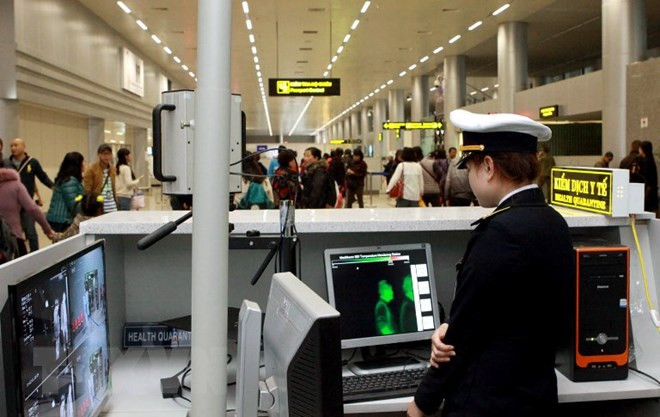  Nhân viên Trung tâm Kiểm dịch Y tế quốc tế kiểm tra thân nhiệt và kê tờ khai y tế cho hành khách. (Ảnh: Dương Ngọc/TTXVN)