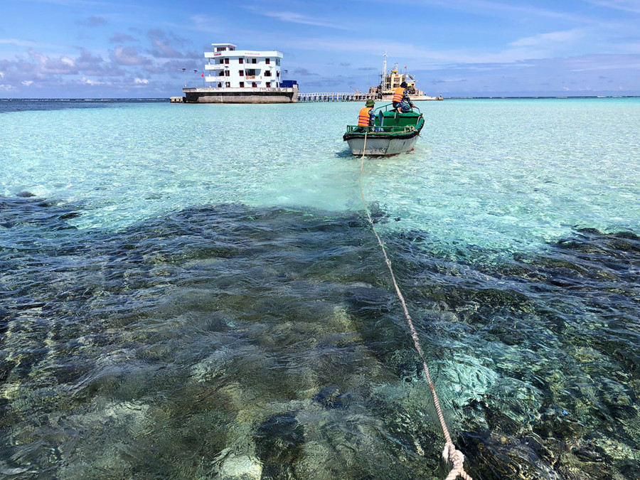 Khu vực đá san hô màu xanh giáp với bãi cát màu trắng, trên luồng kéo xuồng chuyển tải vào đảo Len Đao
