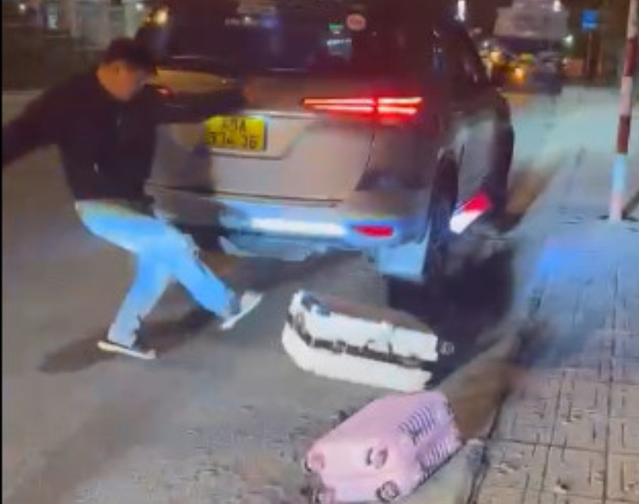 Tài xế taxi đưa chất "sút" văng va li của du khách vào lề đường. Ảnh chụp lại từ clip Tài xế taxi đưa chất