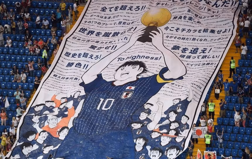 Hình ảnh Tsubasa nâng cao chiếc Cúp vô địch được cổ động viên Nhật Bản mang đến khán đài nước Nga năm 2018. Ảnh: FIFA