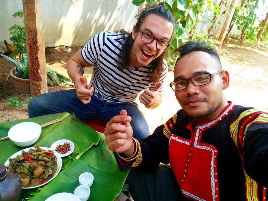  Anh Rcom Dam Mơ Ai (bìa phải) hướng dẫn nhiếp ảnh gia-nhà làm phim Stephen Parcalidis cách chế biến, thưởng thức ẩm thực của người Jrai (ảnh nhân vật cung cấp).