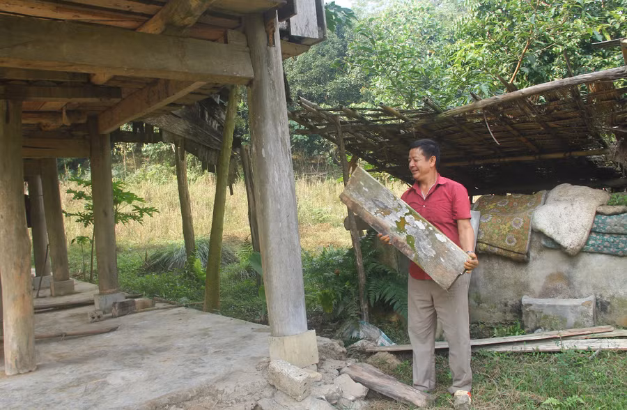  Ông Vi Văn Danh và khúc gỗ nhà sàn của gia đình ông bị voi rừng quật gãy. Ảnh: K.HOAN