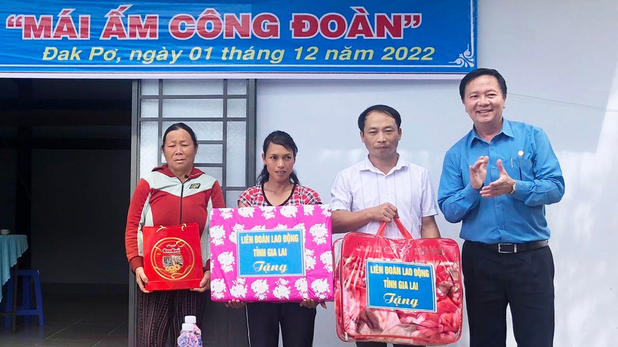 Đồng chí Nguyễn Ngọc Minh- Phó chủ tịch thường trực LĐLĐ tỉnh (Áo xanh) tặng quà của LĐLĐ tỉnh cho hộ anh Lý Văn Khào tại lễ bàn giao nhà. (ẢNH: NGUYỄN HIỀN).