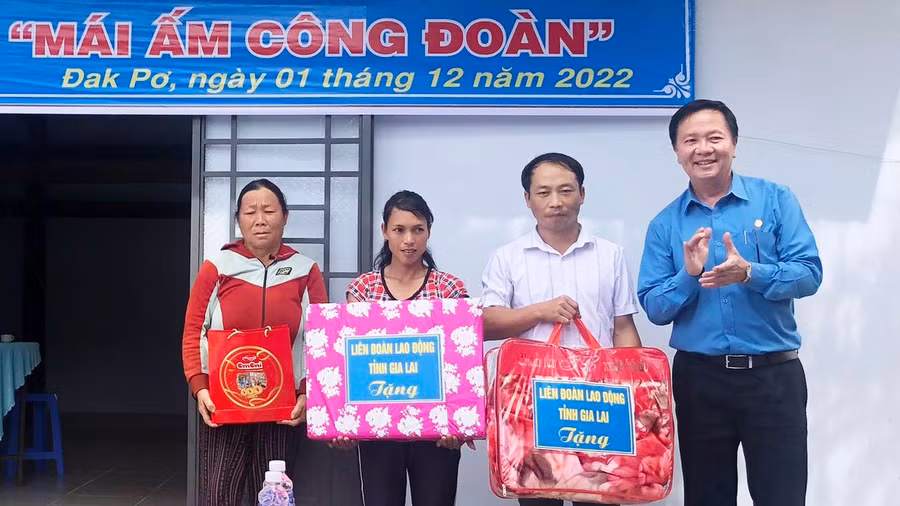 Đồng chí Nguyễn Ngọc Minh- Phó chủ tịch thường trực LĐLĐ tỉnh (Áo xanh) tặng quà của LĐLĐ tỉnh cho hộ anh Lý Văn Khào tại lễ bàn giao nhà. (ẢNH: NGUYỄN HIỀN).