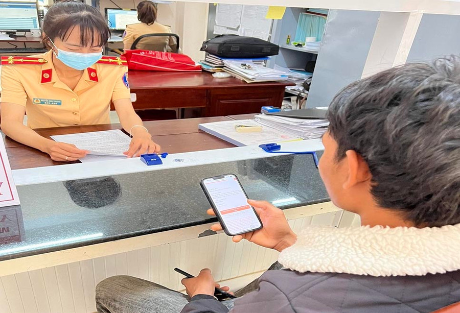 Cán bộ hướng dẫn người dân sử dụng dịch vụ công trực tuyến để nộp phạt vi phạm hành chính trong lĩnh vực giao thông đường bộ. Ảnh: Phan Yến