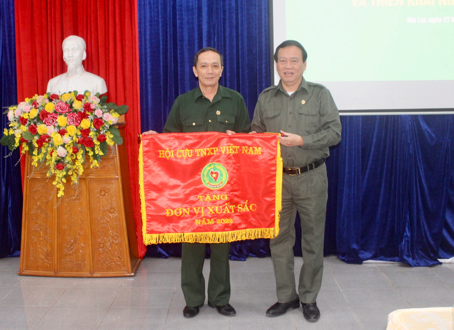Đồng chí Vũ Trọng Kim (bìa phải)-Chủ tịch Hội Cựu TNXP Việt Nam tặng cờ thi đua đơn vị xuất sắc năm 2022 cho Hội Cựu TNXP tỉnh Gia Lai. Ảnh: Phan Lài