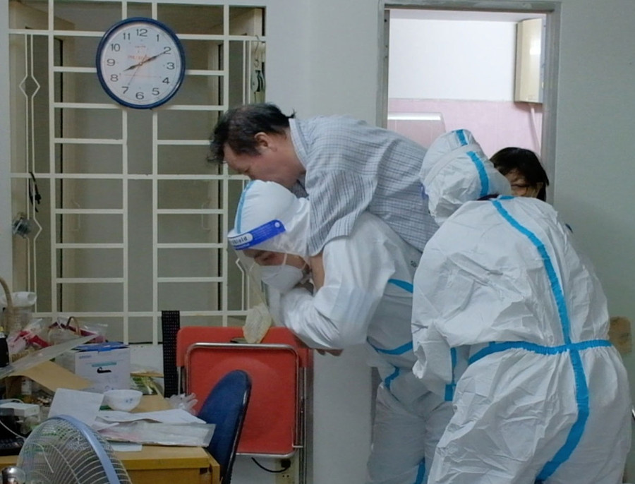 Cõng người bệnh xuống lầu, di chuyển ra xe cứu thương. Ảnh: Lê Vân