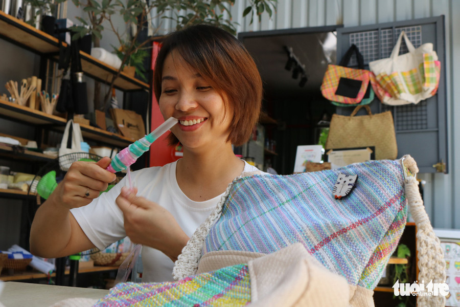 Chị Thu Trang (32 tuổi, Q. Bình Tân), chủ quán cà phê Nắng, là người kết hợp cùng Hằng mở cửa hàng bán những sản phẩm organic. Trong ảnh, chị Trang đang cuộn những sợi nilông để dễ dệt, bên cạnh là chiếc túi thành phẩm - Ảnh: HOÀNG AN