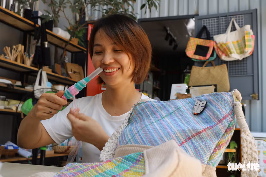 Chị Thu Trang (32 tuổi, Q. Bình Tân), chủ quán cà phê Nắng, là người kết hợp cùng Hằng mở cửa hàng bán những sản phẩm organic. Trong ảnh, chị Trang đang cuộn những sợi nilông để dễ dệt, bên cạnh là chiếc túi thành phẩm - Ảnh: HOÀNG AN