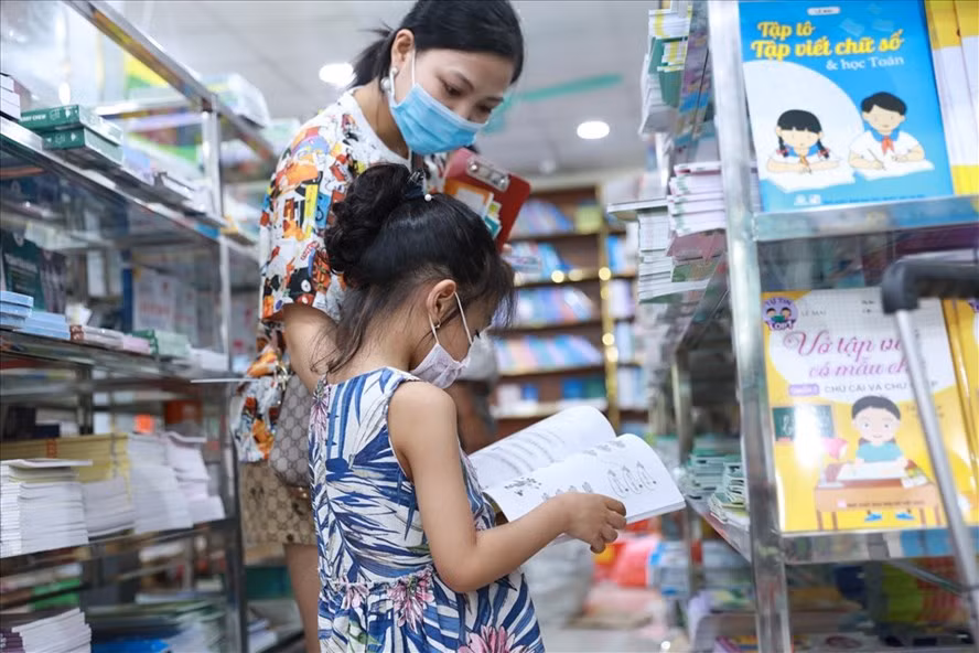 Phụ huynh đưa con chọn sách giáo khoa và sách tham khảo lớp 1 tại một nhà sách ở Hà Nội. Ảnh: Hải NGuyễn