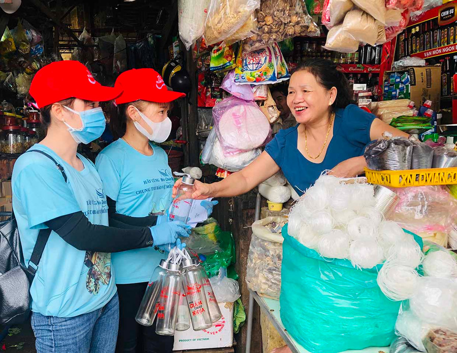  Nhân viên Văn phòng Tổng đại lý Prudential Gia Lai tặng chai đựng nước thủy tinh cho các tiểu thương Trung tâm Thương mại Pleiku. Ảnh: Phan Lài