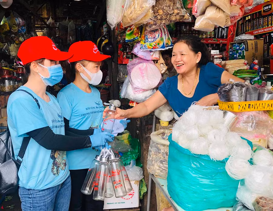  Nhân viên Văn phòng Tổng đại lý Prudential Gia Lai tặng chai đựng nước thủy tinh cho các tiểu thương Trung tâm Thương mại Pleiku. Ảnh: Phan Lài