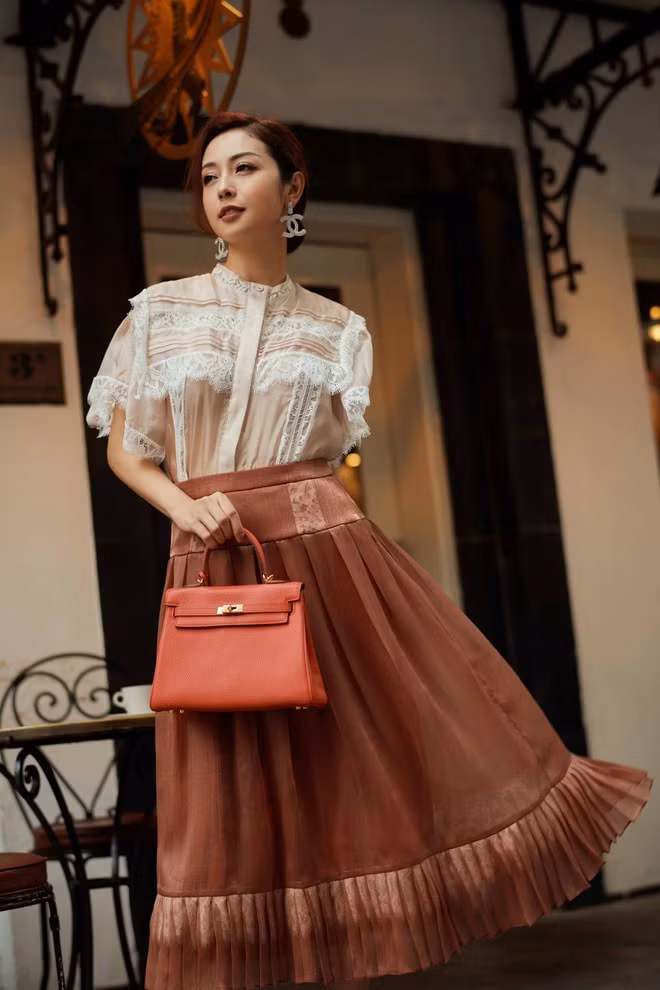 Bên cạnh đó, Hoa hậu Jennifer Phạm còn gợi ý cho các tín đồ thời trang bằng một thiết kế áo blazer kết hợp với chân váy xếp ly đính kết tinh xảo trên nền chất liệu tơ nhũ phối ren màu cam đất. Cách phối hợp này khiến cho tổng thể bộ trang phục vừa toát lên vẻ trẻ trung vừa mang không khí của mùa thu. ẢNH: NVCC