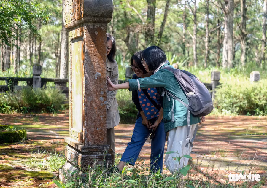  Một nhóm du khách tập dịch chữ Nôm ghi trên bia đá ở sân khu lăng mộ - Ảnh: M.VINH