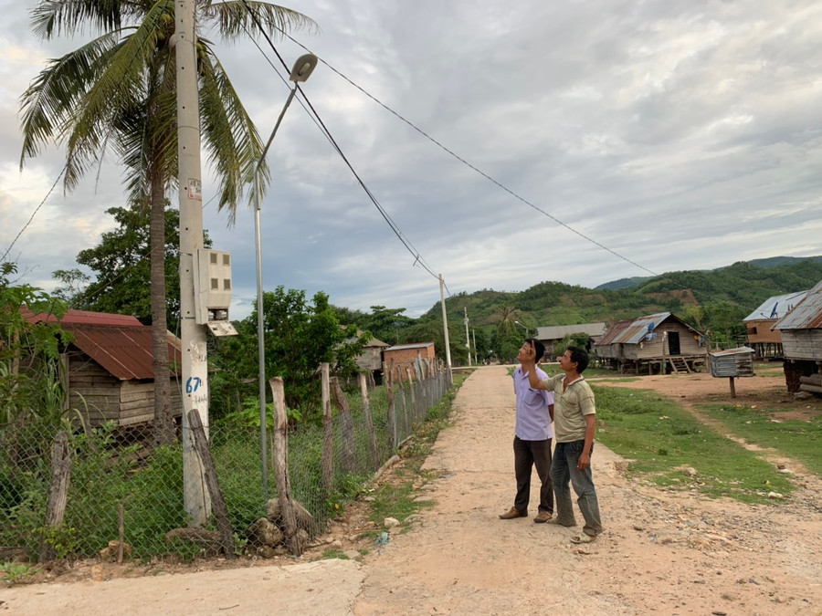 Anh Nay Đă (bìa phải, Bí thư Chi bộ buôn Chư Băh A, xã Chư Băh, thị xã Ayun Pa) giới thiệu hệ thống đèn chiếu sáng do chính mình lắp đặt. Ảnh: Vũ Chi 
