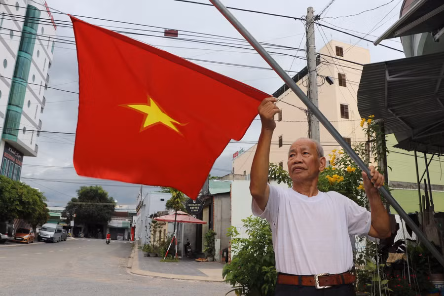 Ông Lê Văn Trữ (tổ 3, phường Tây Sơn, thị xã An Khê) treo cờ Tổ quốc chào mừng Đại hội đại biểu Đảng bộ tỉnh lần thứ XVI. Ảnh: Ngọc Minh