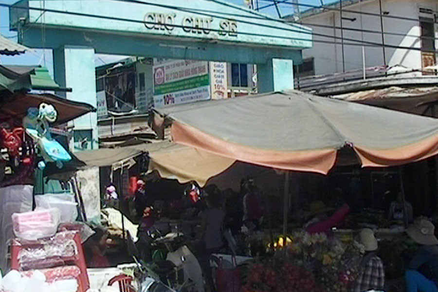 Các tiểu thương buôn bán ngay trước cổng chợ, sát với lòng đường quốc lộ 14. Ảnh: Công Dũng