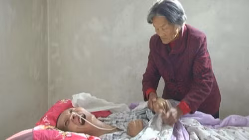 Anh Wang Shubao tỉnh dậy nhìn thấy dòng nước mắt lăn dài trên gương mặt người mẹ già đã chăm sóc anh hơn một thập kỷ qua. Ảnh: Jining News Network.
