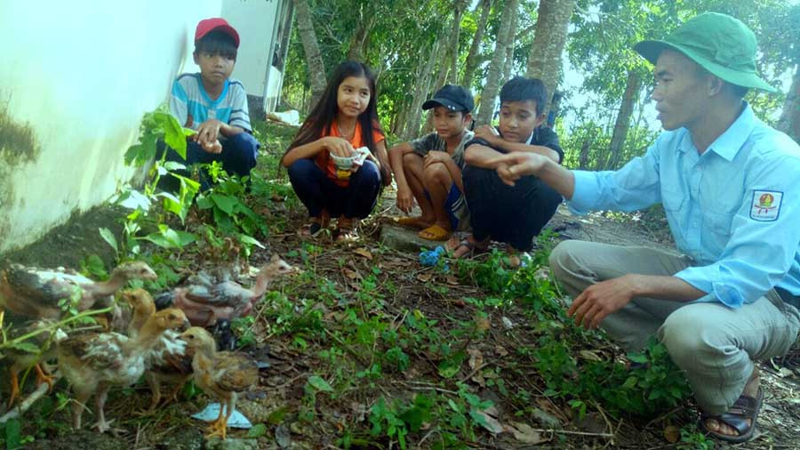  Thầy Trương Công Hương hướng dẫn các em học sinh cách chăm sóc đàn gà. Ảnh: T.B