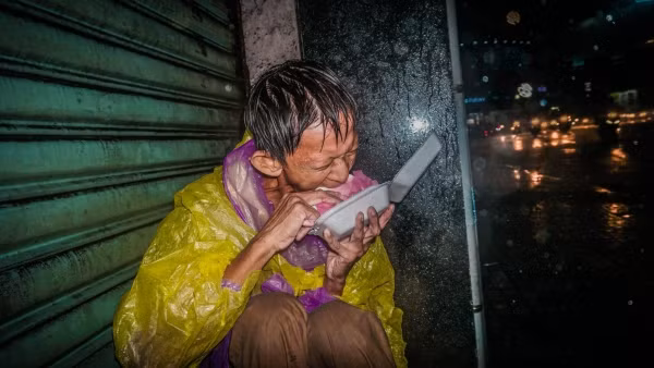 Khoảnh khắc người đàn ông vô gia cư co ro trong mưa gió lớn ở Sài Gòn gây xúc động. Ảnh: Huỳnh Quang Huy.