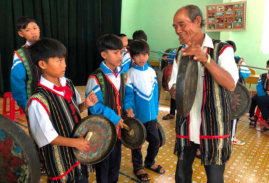  Nghệ nhân Đinh Du đang hướng dẫn cách đánh chiêng cho các em học sinh. Ảnh: p.l