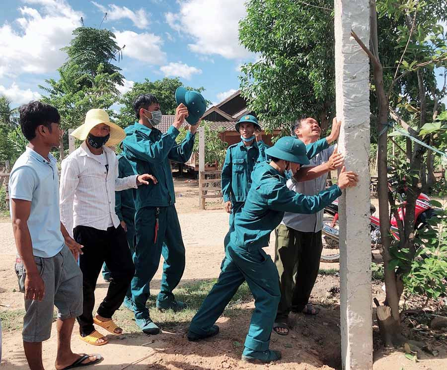  Lực lượng dân quân và các đoàn thể giúp nhân dân buôn Mlah rào vườn, dọn dẹp vệ sinh, di chuyển chuồng trại nuôi nhốt gia súc. Ảnh: N.M