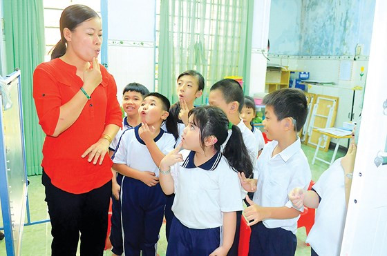  Cô Lâm Thị Minh Châu, giáo viên Trường chuyên biệt Hy vọng quận 8, tập các cháu đánh vần. Thầy cô dạy trẻ khiếm thính thường mất nhiều thời gian và công sức, muốn các em ghi nhớ một điều gì thì luôn phải nhắc đi nhắc lại rất nhiều lần, vừa dùng ngôn ngữ ký hiệu, vừa kết hợp với khẩu hình miệng để dạy các em phát âm cho quen. Những điều ấy đã ươm mầm cho bao ước mơ, hoài bão của các em… Ảnh: THANH HÙNG