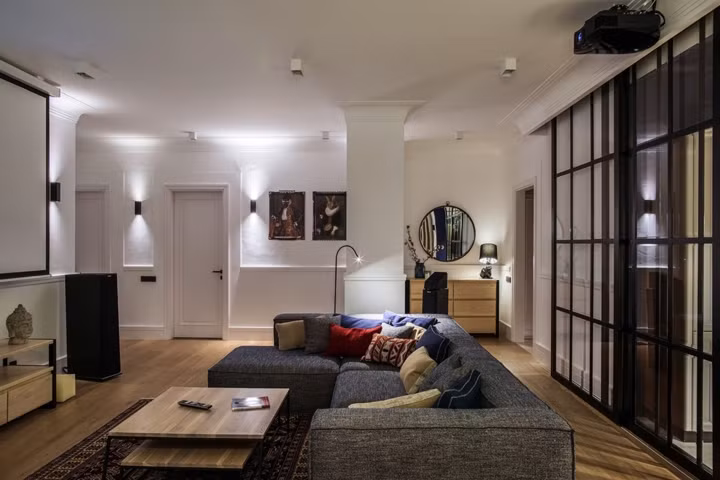 Chủ nhà chọn sơn tường màu trắng để dễ dàng làm nền trong trang trí, màn hình máy chiếu đối diện với ghế sofa mang lại những phút giây thư giãn thoải mái cho các thành viên trong nhà. 