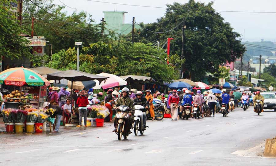 trong khi cách đó không xa, các tiểu thương họp chợ tự phát ngay bên lề quốc lộ 14 (ảnh nhỏ). Ảnh: M.N