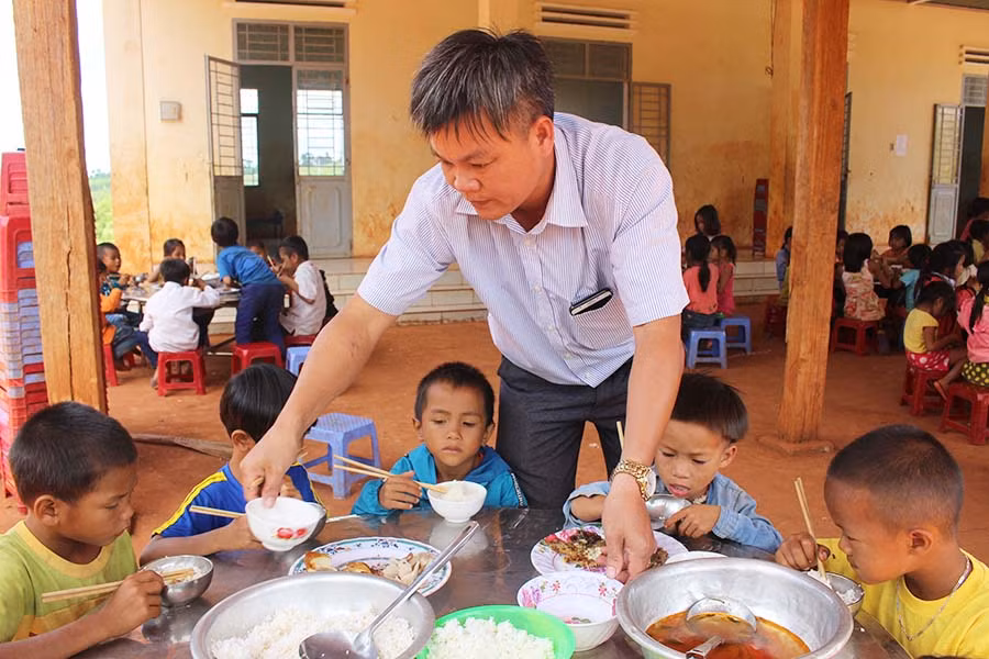 Thầy Nguyễn Thế Anh-Hiệu trưởng Trường Phổ thông Dân tộc Bán trú Tiểu học và THCS Đak Smar chia thức ăn cho học trò. Ảnh: N.G