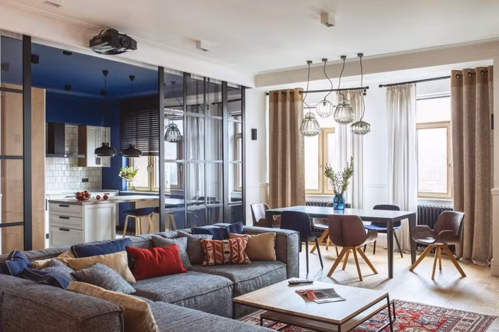 Bàn ăn đặt gần cửa sổ lấy ánh sáng, bếp cách bàn và phòng khách bởi lớp cửa kính tránh cho mùi thức ăn bay ra ngoài khi nấu nướng.