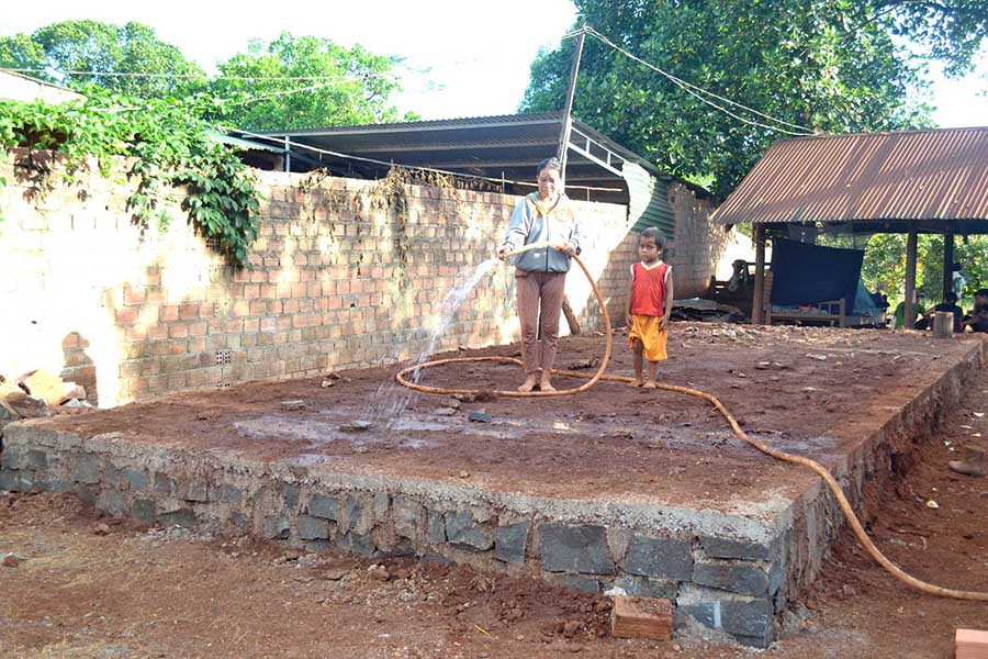  Chị Phyun cùng con út tưới nước cho phần móng ngôi nhà đang thi công. Ảnh: L.H