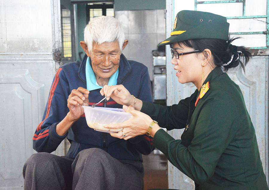  Một nữ quân nhân tận tay đút từng muỗng cháo cho cụ già ở Trung tâm Bảo trợ Xã hội Tổng hợp tỉnh. Ảnh: A.H