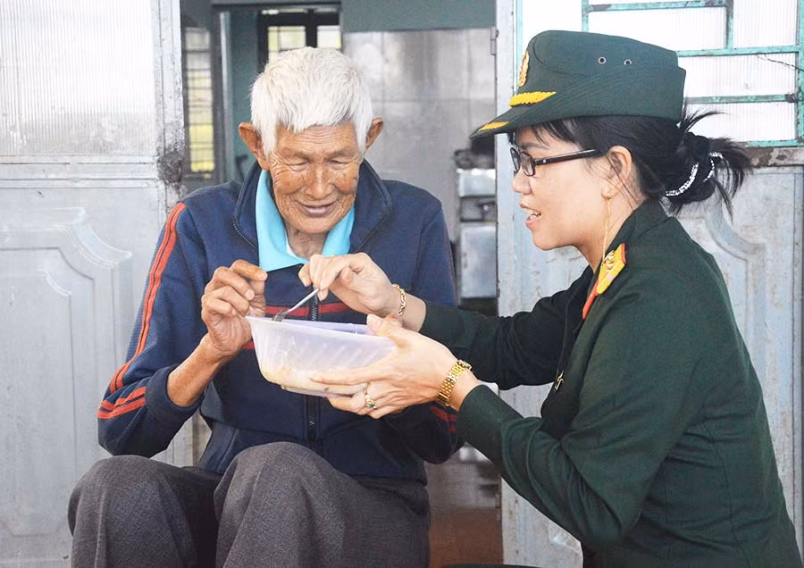  Một nữ quân nhân tận tay đút từng muỗng cháo cho cụ già ở Trung tâm Bảo trợ Xã hội Tổng hợp tỉnh. Ảnh: A.H
