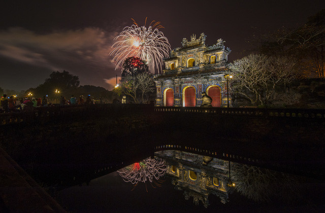Pháo hoa năm mới bừng sáng tỏa bỏng bên cửa Hiển Nhơn (cửa phía Đông của Hoàng thành Huế) và rọi bóng xuống hồ nước đêm huyễn hoặc