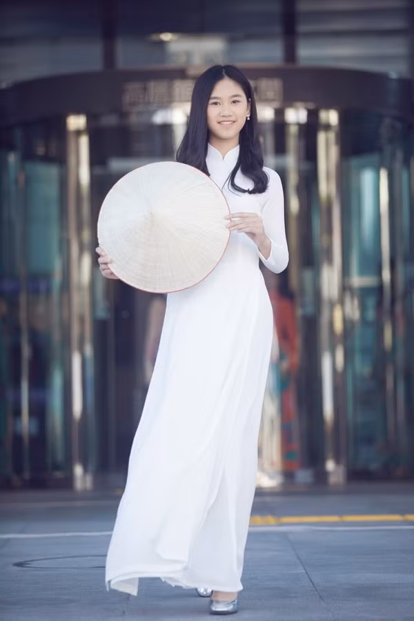  Hồng Uyên, con gái thứ hai của Paris Vũ, mặc áo dài trắng cùng nón lá. Cô bé năm nay 13 tuổi, hiện học tại một trường quốc tế ở TP HCM.