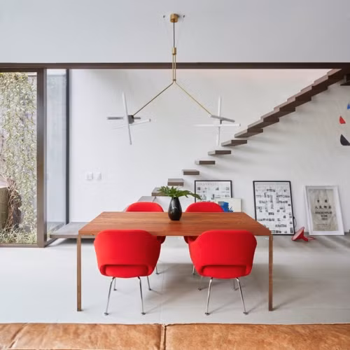 4 chiếc ghế màu đỏ cùng bàn gỗ đặt cạnh khu vực nhà bếp là bàn ăn chính và là nơi học bài của những đứa trẻ.