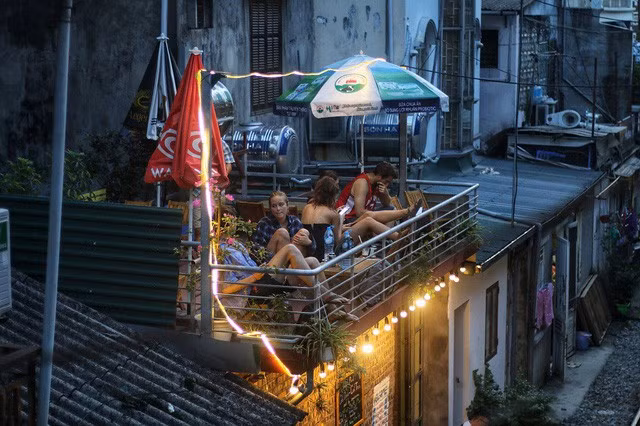 Những du khách nước ngoài ngồi đợi chuyến tàu tối lúc 19h tại một quán cà phê nhỏ ở xóm đường tàu. Ảnh: Thanh Thúy