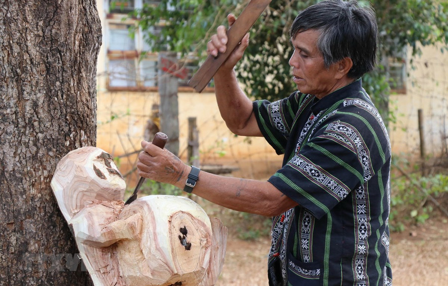 Nghệ nhân ưu tú Ksor Krôh tạc tượng dân gian Tây Nguyên. (Ảnh: Hồng Điệp/TTXVN) 