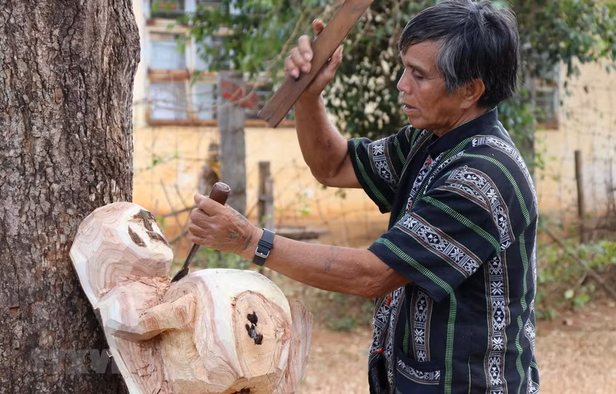 Nghệ nhân ưu tú Ksor Krôh tạc tượng dân gian Tây Nguyên. (Ảnh: Hồng Điệp/TTXVN) 