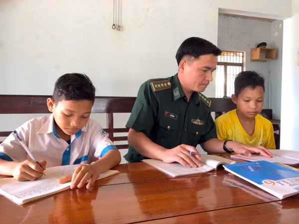 Đại úy Lê Tuấn Anh tranh thủ hướng dẫn 2 cháu là con nuôi của đơn vị học tập. Ảnh: A.H