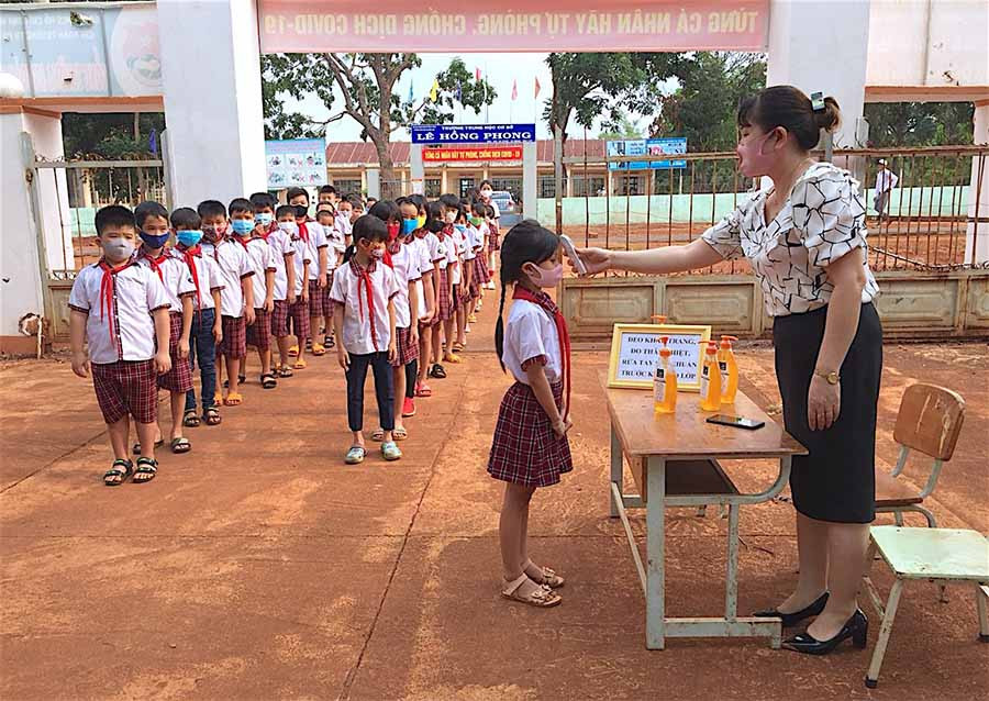 Giáo viên Trường Tiểu học Cù Chính Lan (xã Ia Chía, huyện Ia Grai) đo thân nhiệt cho học sinh trước khi vào lớp. Ảnh: H.T