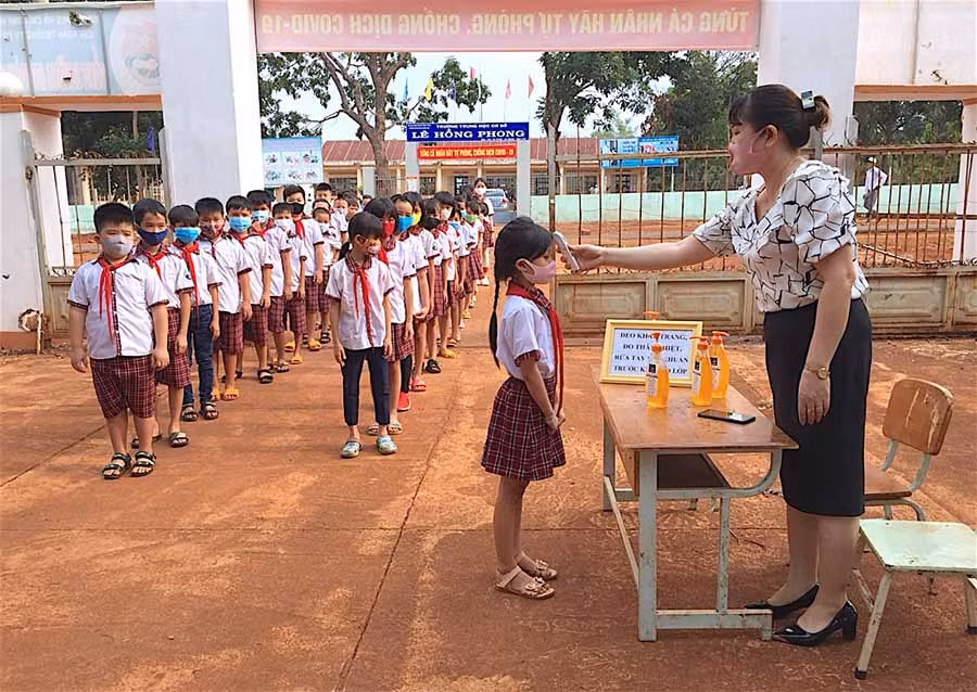 Giáo viên Trường Tiểu học Cù Chính Lan (xã Ia Chía, huyện Ia Grai) đo thân nhiệt cho học sinh trước khi vào lớp. Ảnh: H.T