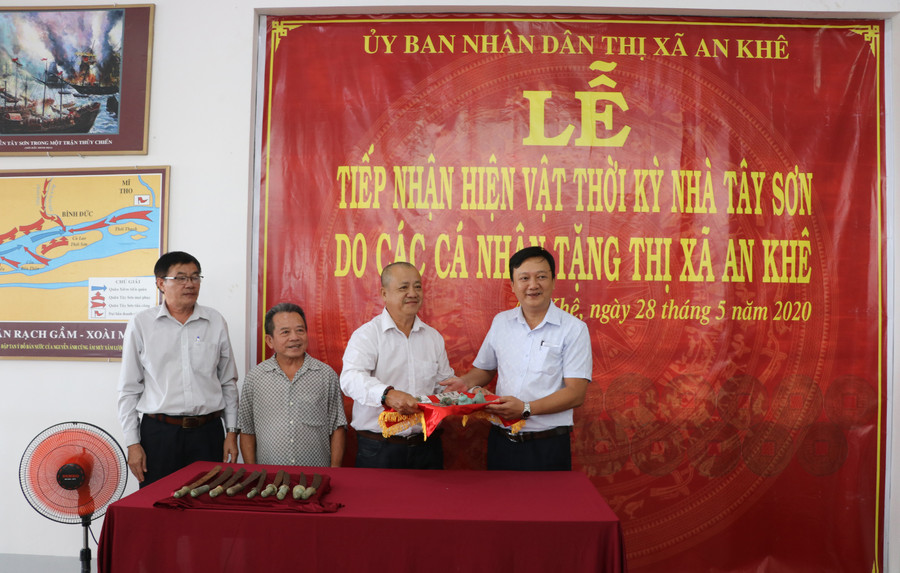 Ông Lâm Dũ Xênh (thứ 3 bên trái; huyện Bình Sơn, tỉnh Quảng Ngãi) trao tặng 99 đồng tiền và 8 cái lục lạc đồng thời kỳ nhà Tây Sơn cho thị xã An Khê. Ảnh: Ngọc Minh
