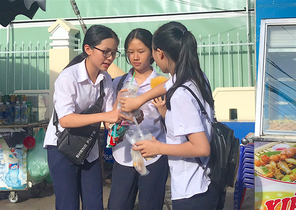 Các em học sinh của Trường THCS Nguyễn Huệ (TP. Pleiku) sử dụng đồ ăn vặt được mua gần trường. Ảnh: M.T